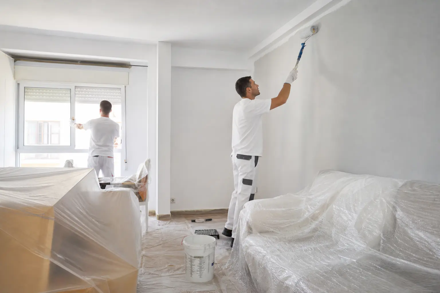 Dos pintores trabajando en un piso amueblado con muebles protegidos en Zaragoza